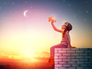 a child sitting on a brick wall with a toy airplane.